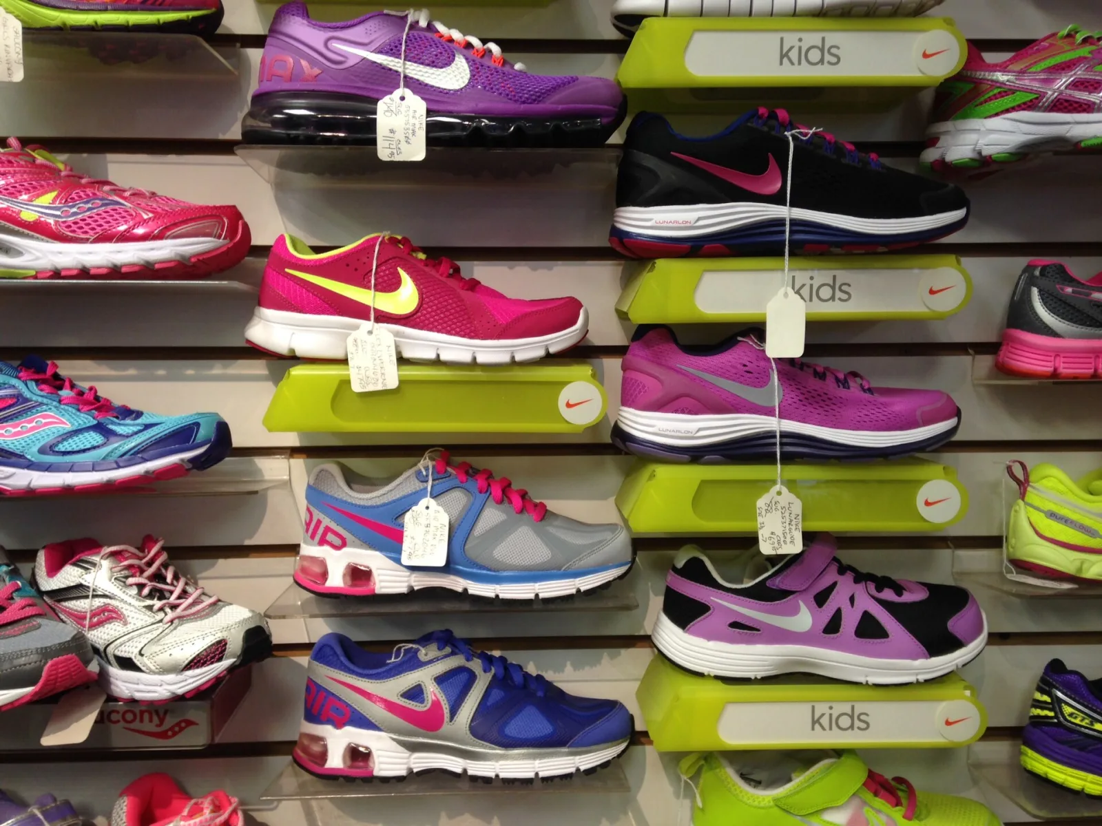A wall of running shoes in many colourways, each with a hanging price tag